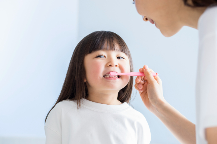 子どもの虫歯を予防するために自宅で歯磨きをする親子