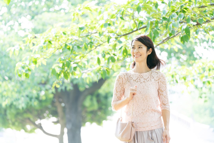 新緑の中を歩く笑顔の女性